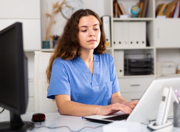 Healthcare professional working on a laptop.