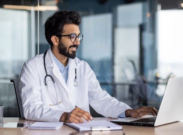 Doctor working on laptop at desk.