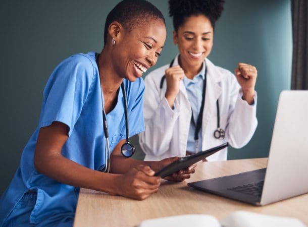 Doctors celebrating while looking at a laptop.