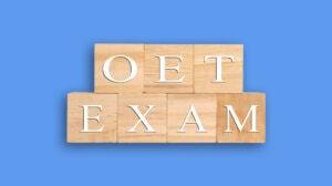 Wooden blocks spell out 'OET EXAM' against a blue background.