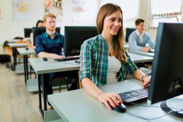 Smiling woman working on computer in classroom